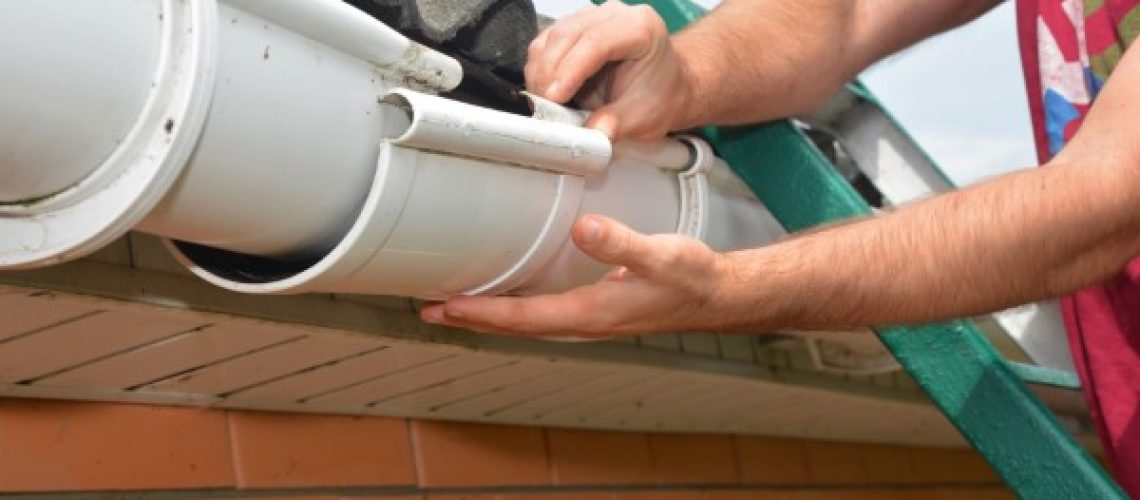 Gutter pipeline installation. Roofer contractor installing and repair rain gutter. Guttering repair with contractor hands.